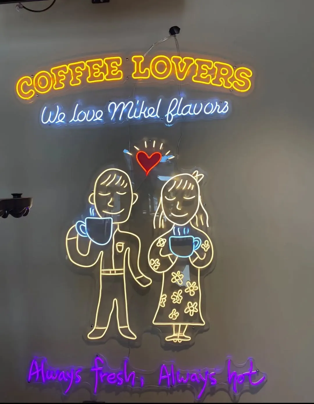 Kahve içen çift illüstrasyonu ve 'Coffee Lovers' yazısıyla çok renkli neon
