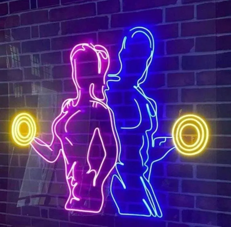 Pink and blue woman and man figure neon with dumbbells on a brick wall