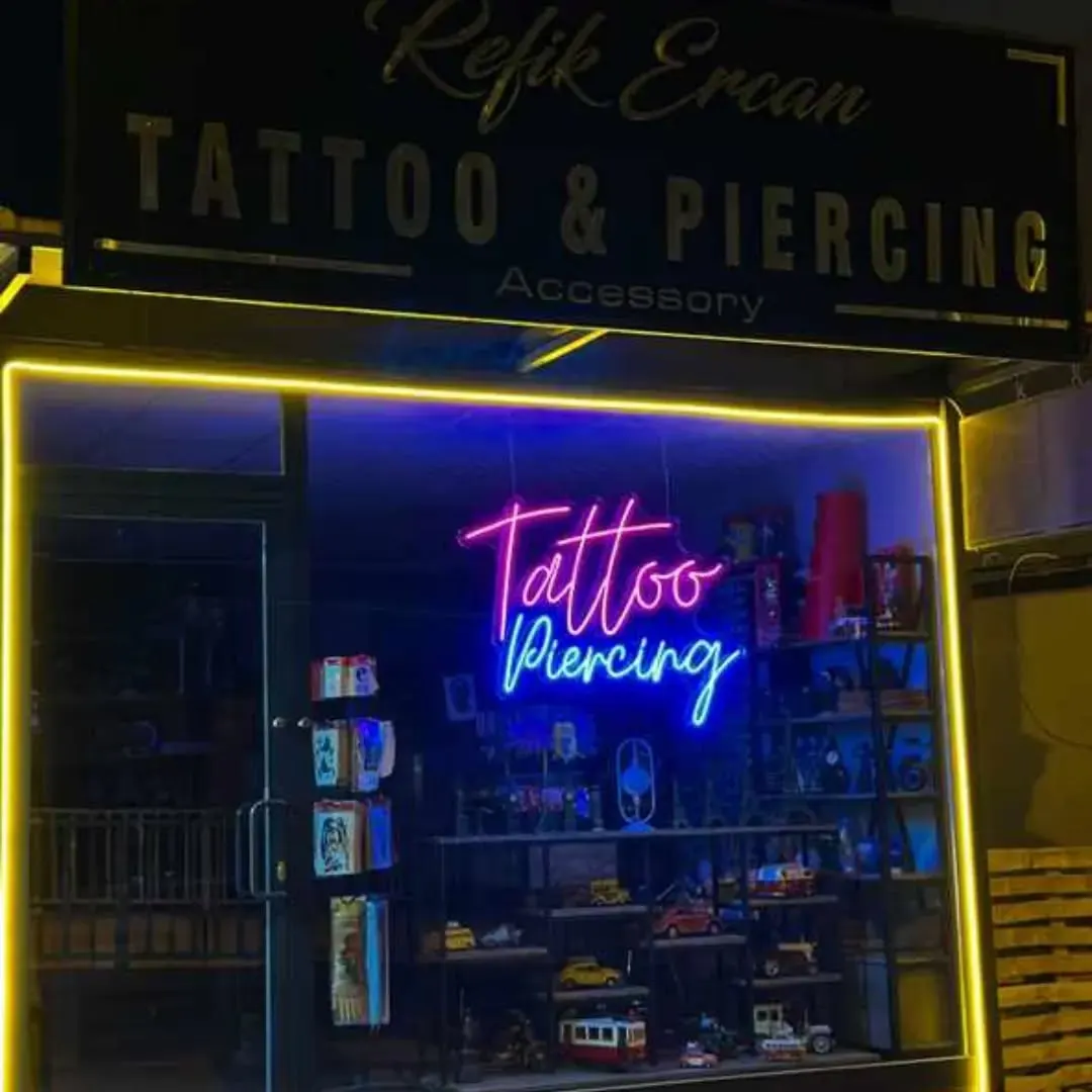 Dövme stüdyosu vitrininde mavi el yazısı neon ve sarı ışıklı çerçeve