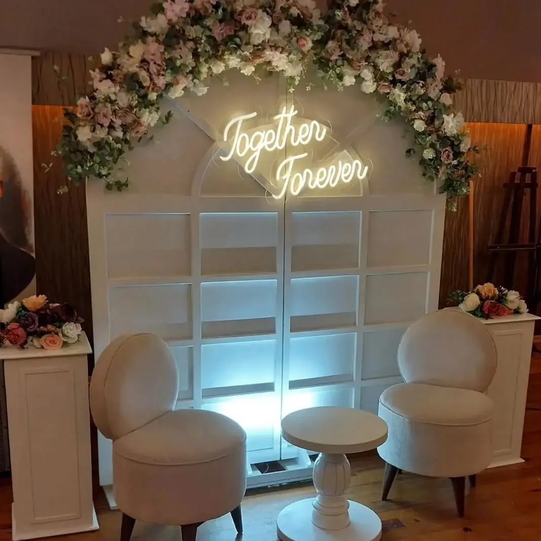 Çiçekli düğün takında beyaz el yazısı 'Together Forever' neonu