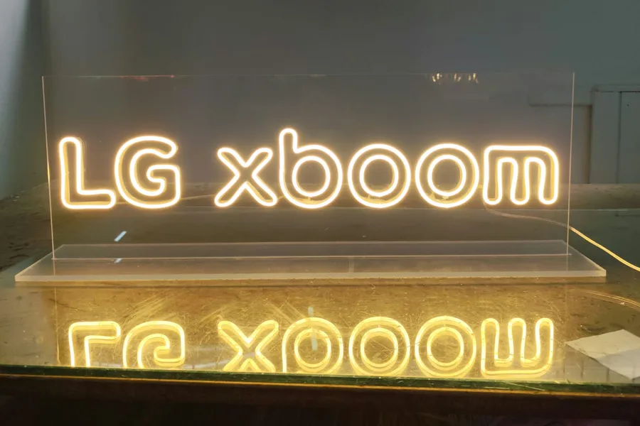 Warm white 'LG xboom' desktop neon sign on a clear acrylic stand